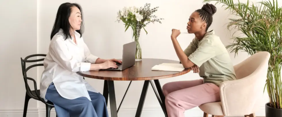 Two women in discussion sitting at a table