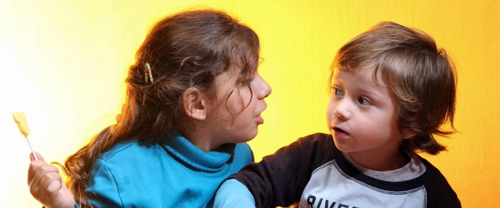 Two children sitting together eating snacks